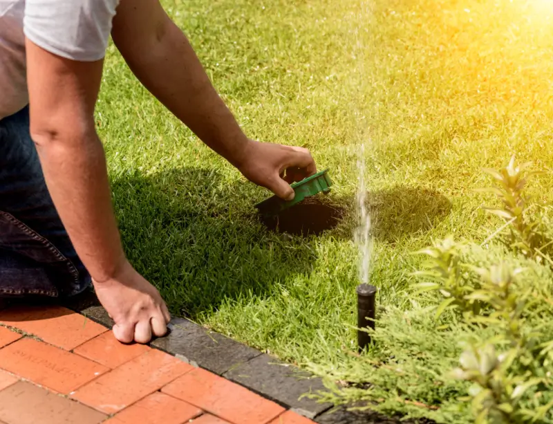 Landscaper performing irrigation maintenance services.