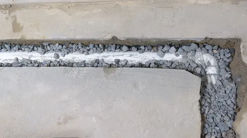An unfinished French drain, showing pipe and drainage gravel.